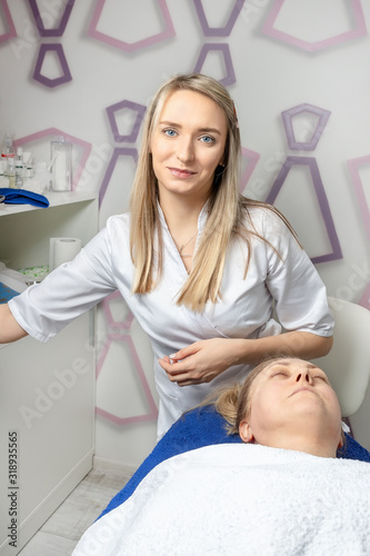 Young attractive beautician doctor making anti-age procedures, mask and peeling for mid-aged female client at beauty clinic. Cosmetologist specialist doing skincare treatment .Health care therapy