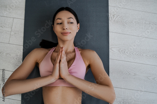 Shot from above a young woman athlete doing yoga, lying on the floor and controls her breathing, relaxation and calm, meditation at home and morning exercises