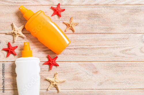 Sunscreen bottles with seashells and starfish on wooden table with copy space. flat lay concept of summer travel vacation photo