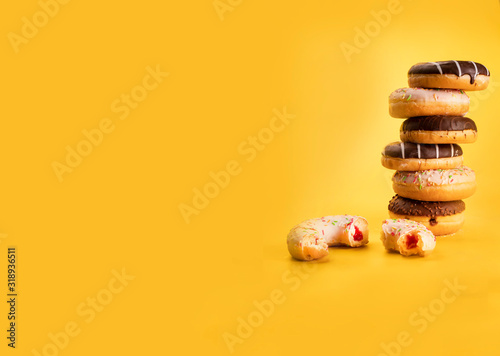Poster with pile of various donuts on yellow background, with copy space. Sweet pastries of Fat Thursday. Doughnuts photo