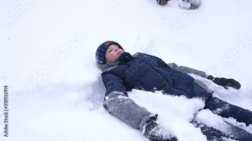 the baby lies on snow and making a snow angel in slowmotion