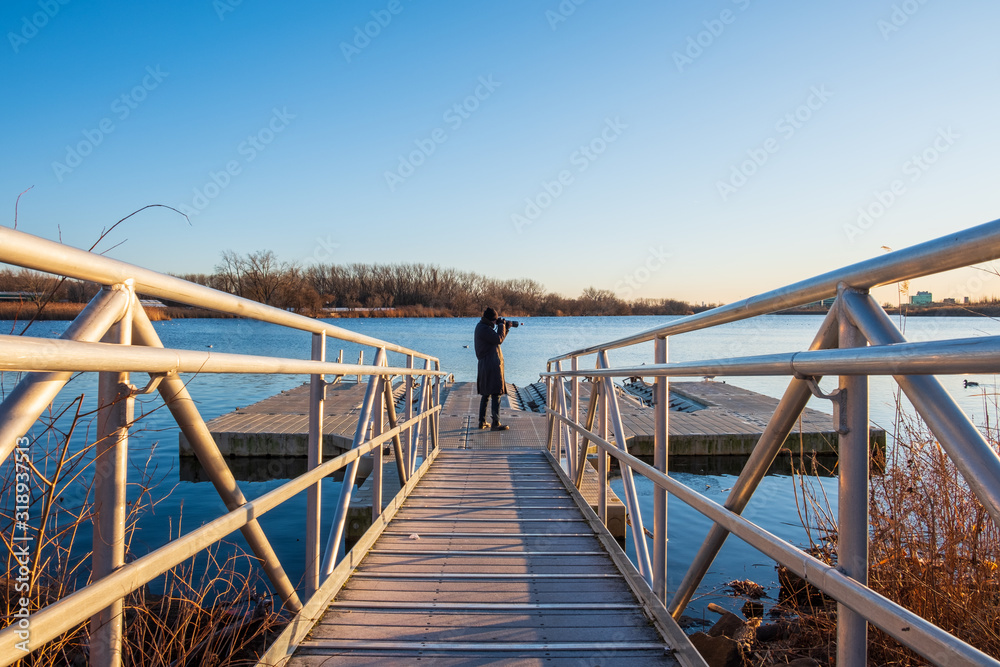 Walkway ramp to lake boat dock. Steel ramp walkway leading to boat dock. Nature photographer standing on boat dock. Walkway ramp to lake boat dock. Steel ramp walkway leading to boat dock. Nature photographer standing on boat dock.