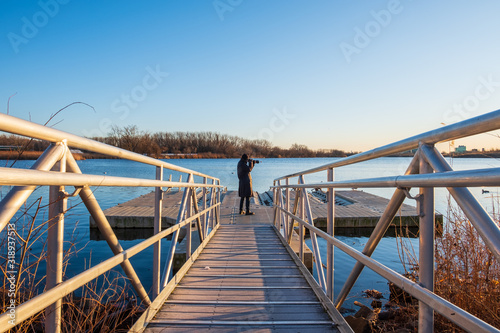 Walkway ramp to lake boat dock. Steel ramp walkway leading to boat dock. Nature photographer standing on boat dock.