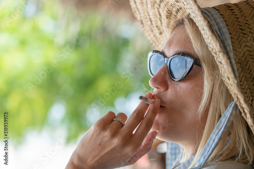 The young woman who is smoking a cigarette and carrying away a smoke in air, closeup