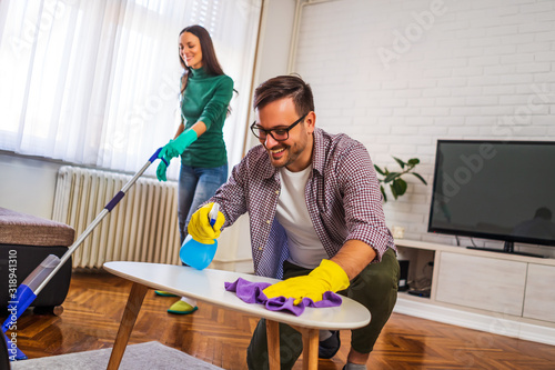 Young happy couple is cleaning their apartment.