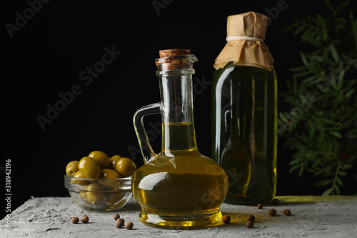 Bottle and jug with olive oil against black background, space for text