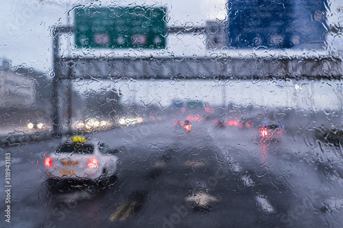 Driving on the highway during heavy rain, view through the windshield of the road and cars. Focus on raindrops.