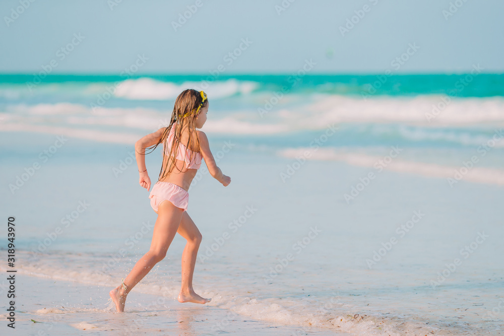 Happy little girl walking at beach during caribbean vacation Happy little girl walking at beach during caribbean vacation