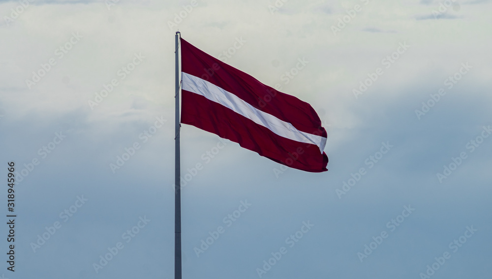 Bordeaux white flag of Latvia against a cloudy sky