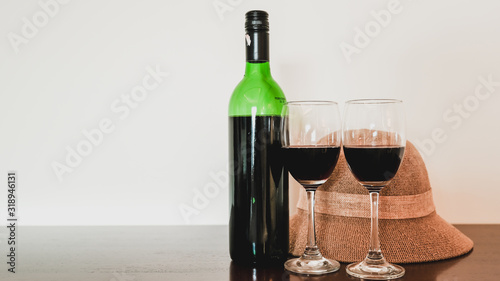 Two glasses of wine and wine bottle with hat on the wooden table