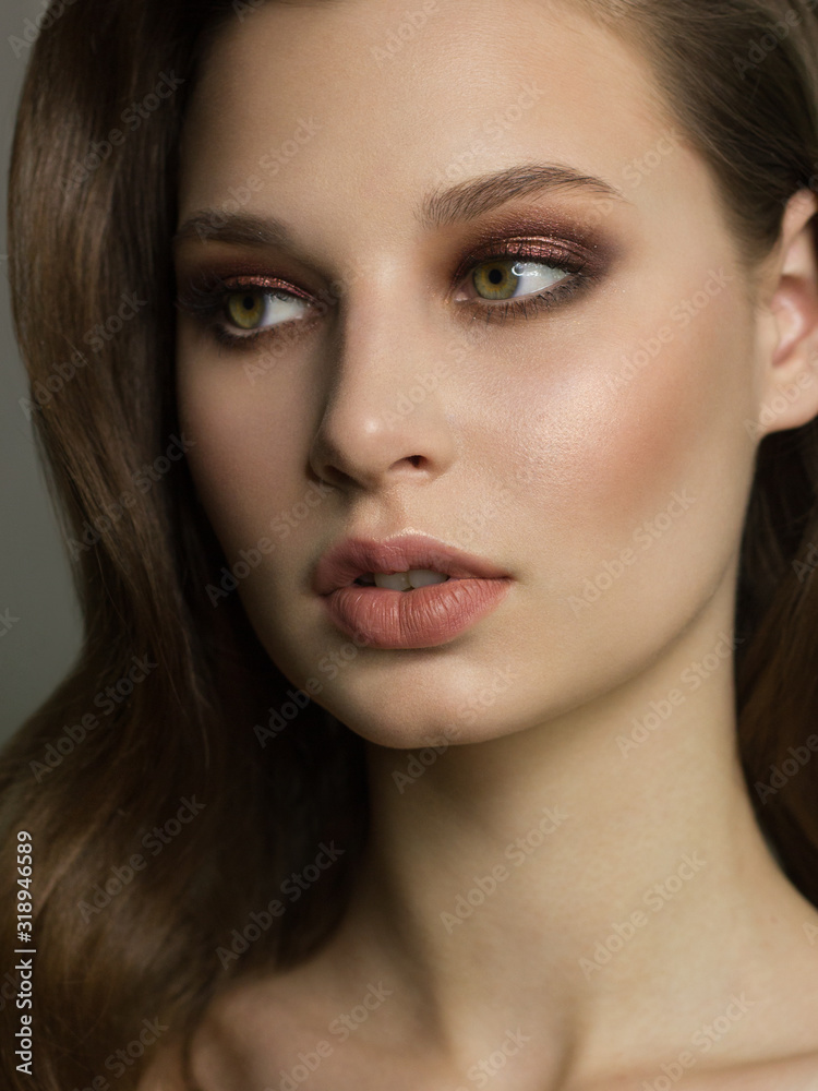 Beautiful brunet model woman face with green eyes and perfect make-up. Portrait of beauty young brunet girl with natural lips and smoky eyes, thick eyesbrow . Female face with clear skin close-up.