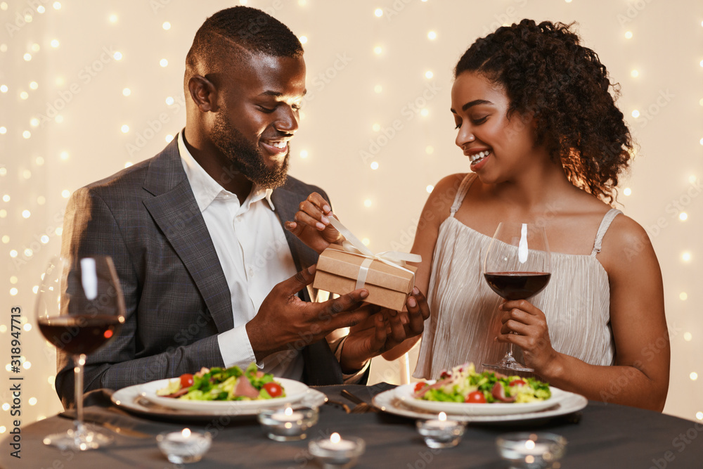 Black man giving to woman beautiful box of present Black man giving to woman beautiful box of present