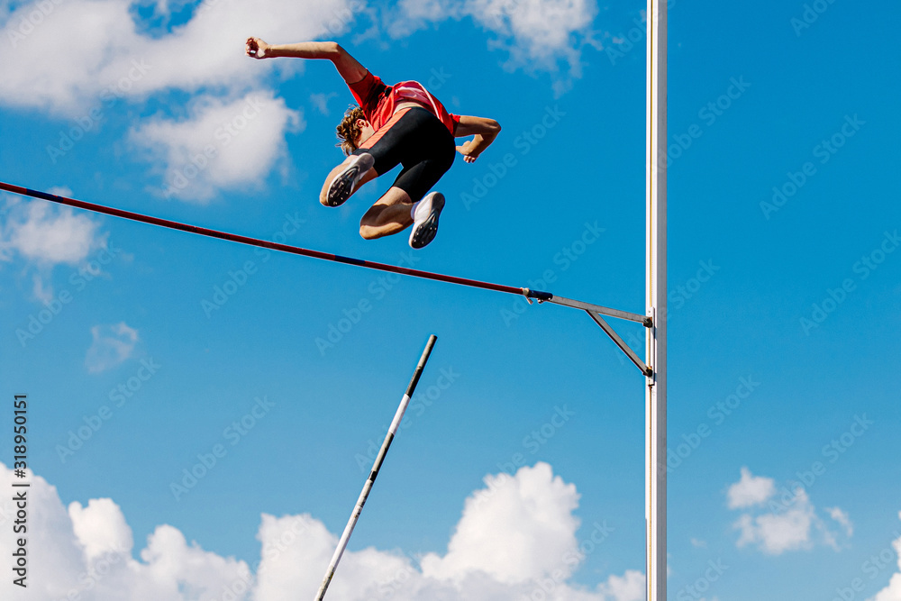 athlete passes bar in pole vault background blue sky and clouds - obrazy, fototapety, plakaty 