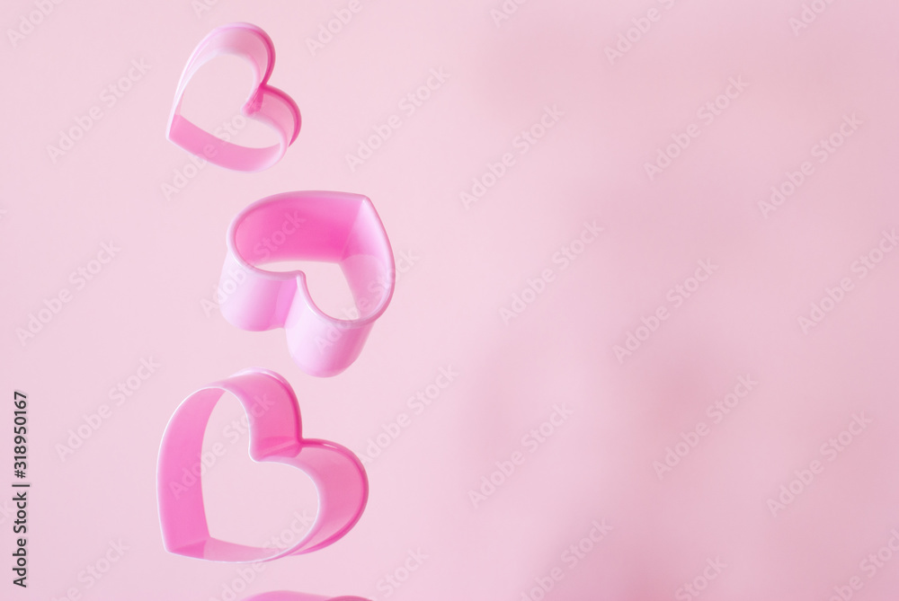 Set of three gentle pink hearts molds of different size levitate on pastel backdrop. Plastic dough cutters or forms for gingerbread cookies. Background with copy space. Set of three gentle pink hearts molds of different size levitate on pastel backdrop. Plastic dough cutters or forms for gingerbread cookies. Background with copy space.