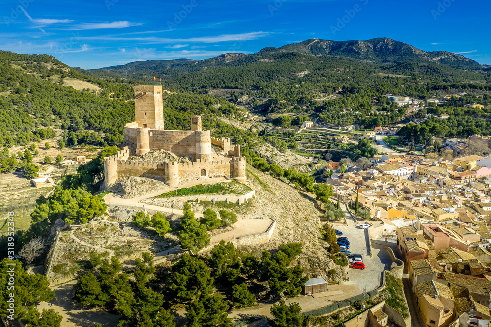 Aerial view of Biar castle in Valencia province Spain with donjon towering over the town and concentric walls reinforced with semi circular towers on a sunny day with blue sky