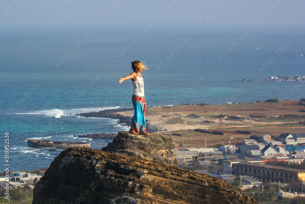 The girl on the cliff on the background of the endless ocean