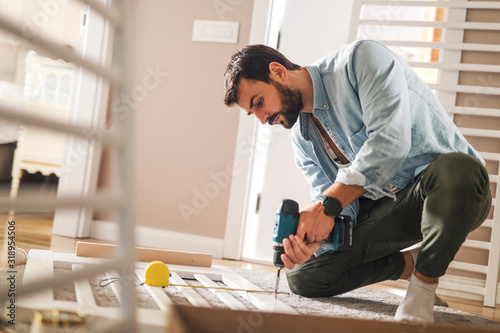 Man securing a baby crib with screwdriver machine. photo