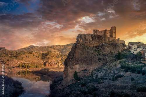 Aerial panoramic view of medieval partially restored Cofrentes castle above the Cabriel river in Spain with reflection and dramatic sky photo