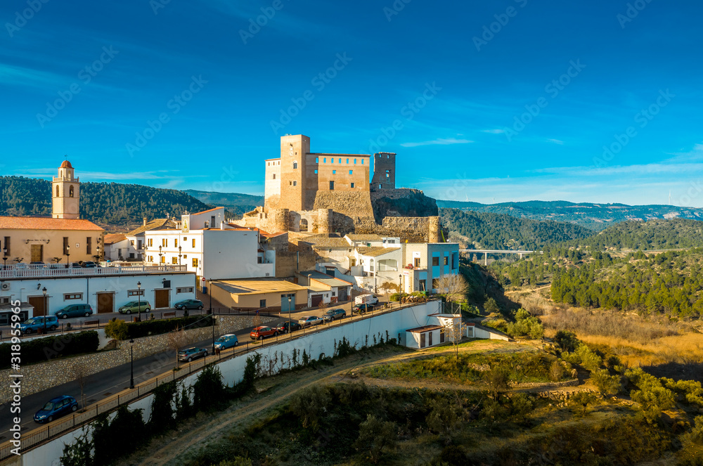 Aerial panoramic view of medieval partially restored Cofrentes castle above the Cabriel river in Spain with reflection and dramatic sky