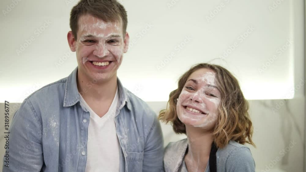Portrait of cute positive couple with smudged with flour face standing in the kitchen. Happy young couple fooling around while cooking food. Close up Portrait of cute positive couple with smudged with flour face standing in the kitchen. Happy young couple fooling around while cooking food. Close up