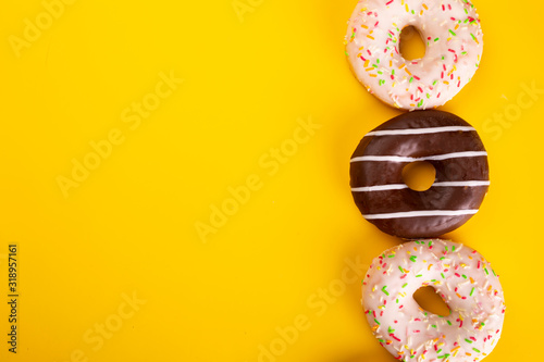Donuts with various toppings on yellow background. Fat Thursday. Poster with doughnuts and text space.