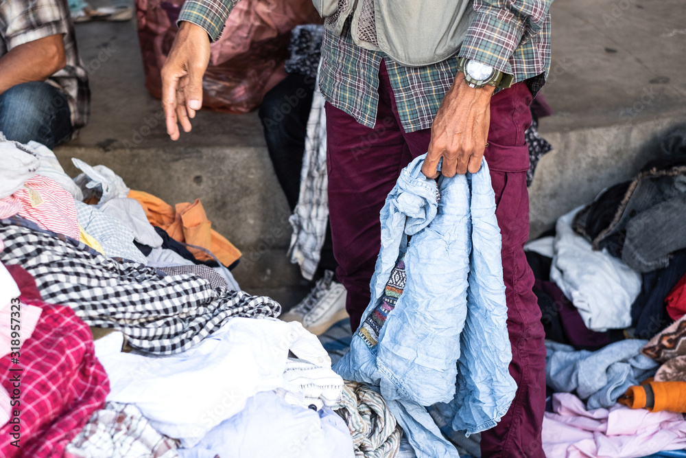 Thai man is choosing used second hand clothes at flea market in Thailand Thai man is choosing used second hand clothes at flea market in Thailand