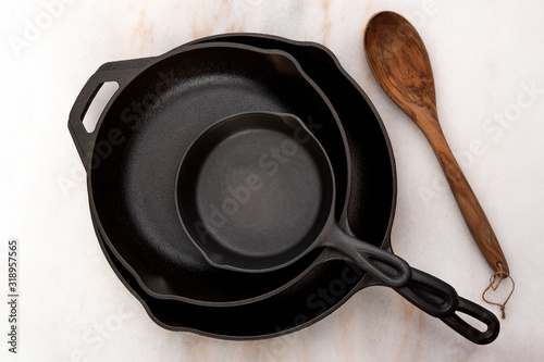 Clean Stacked Cast Iron Skillets on Countertop with Wooden Spoon