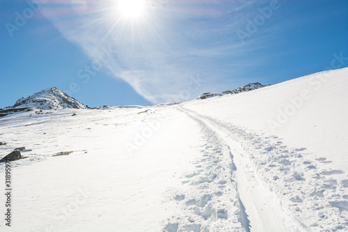 Spectacular winter mountain view with ski trail ascending a slope.