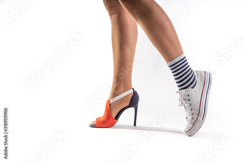 Woman legs wearing different shoes on each foot on white background.