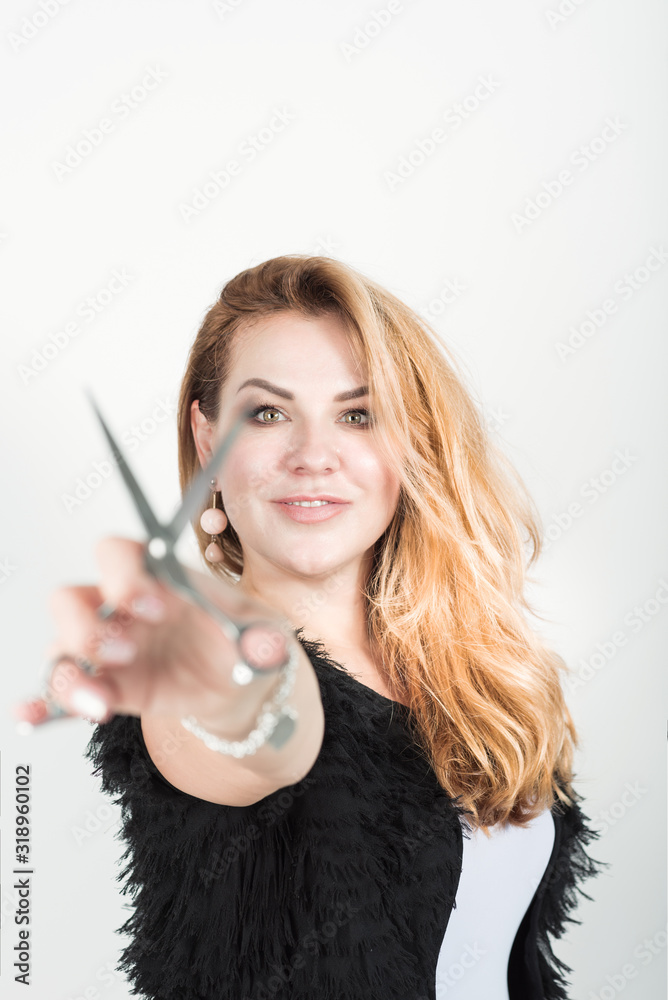 Woman holding hairdresser scissors to the camera on white background - selective focus on the woman Woman holding hairdresser scissors to the camera on white background - selective focus on the woman