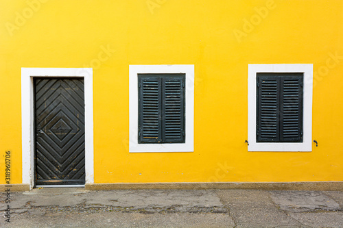 Detail of olf wooden door and window with closed shutters.