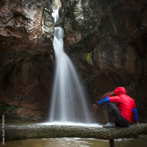 chico con abrigo rojo mirando delante de cascada photo