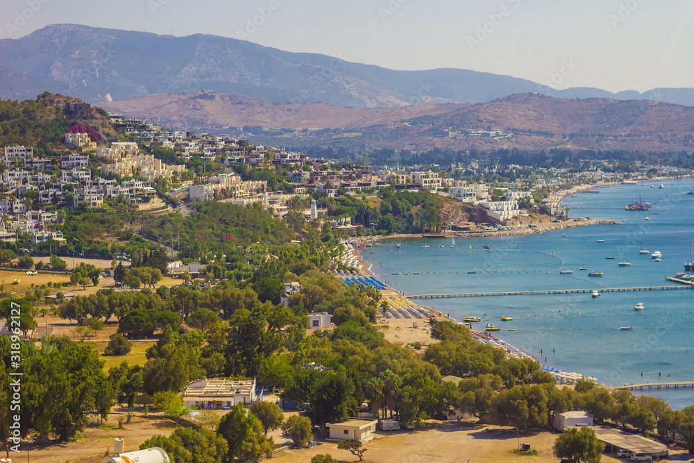 Beautiful panoramic view on Bodrum marina. Turkish beach vacation on the shores of Aegean sea. Stylish white buildings,  green trees on foreground. Bodrum city, Mugla, Turkey. Soft focus