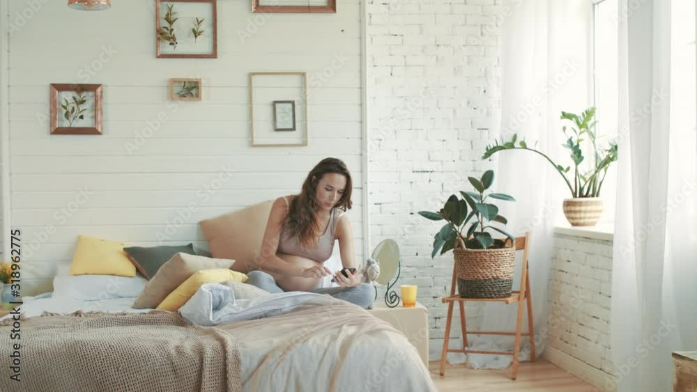 Pregnant woman taking selfie phone in bed. Young expectant mother sitting home. Pregnant woman taking selfie phone in bed. Young expectant mother sitting home.