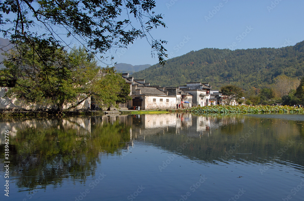 Hongcun Ancient Town in Anhui Province, China. Beautiful view of the old buildings in Hongcun with their reflection in the blue water of Nanhu Lake. The pretty, ancient town of Hongcun in China.