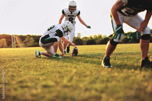 American football players practicing place kicking during a team