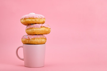Colorful donuts breakfast composition with different color styles of donuts and fresh coffee on pink background