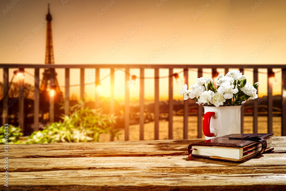 Fresh hot coffee on wooden table and blurred background of Paris city landscape. 