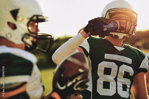 Football player drinking water during a team practice photo