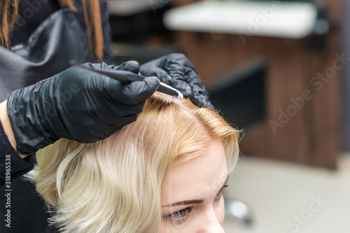 Hairdresser coloring woman's hair in the salon, close up.