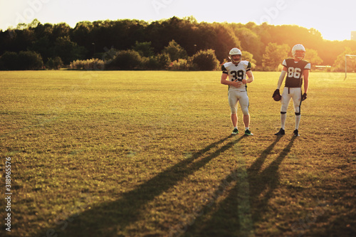 Two football players standing on field in the late afternoon