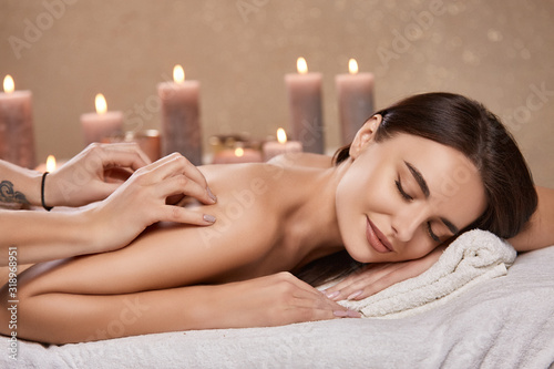 aroma theraphy with candles and massage for woman's back in spa salon