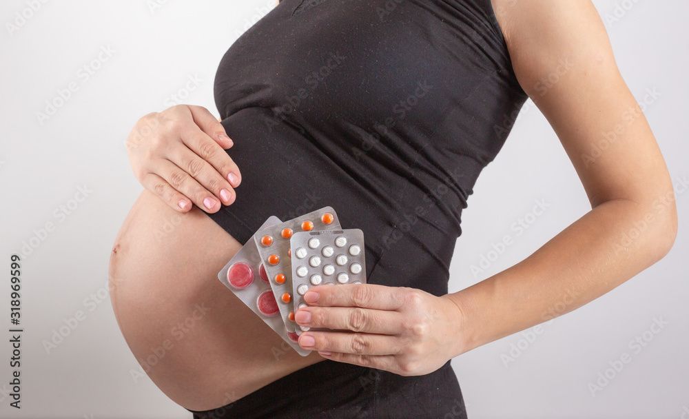 Obraz premium pregnancy, people and health care concept - close up of pregnant woman. vitamins and minerals for pregnant women. Taking medications during pregnancy. Colds and pregnancy. Medicines for pregnant women