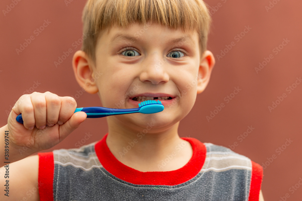 The child holds a toothbrush in his hand near his mouth. The child holds a toothbrush in his hand near his mouth.