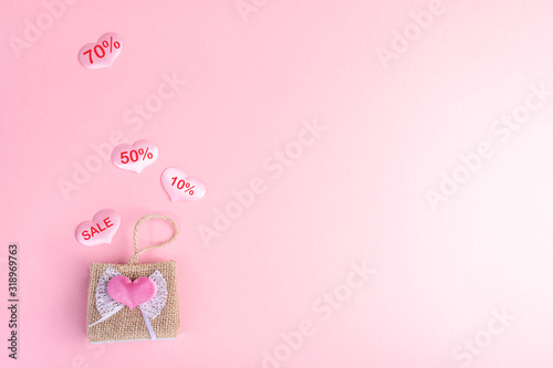 Valentine's day sale concept. Decorative wicker handbag and hearts with discount percentages on pink backdrop.