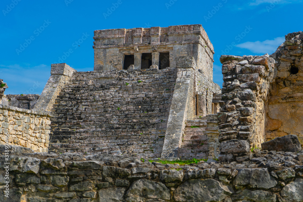 Ruins of ancient Tulum. Architecture of ancient maya. View with temple and other old buildings, houses. Blue sky and lush greenery of nature. travel photo. Wallpaper or background. Yucatan. Mexico. Ruins of ancient Tulum. Architecture of ancient maya. View with temple and other old buildings, houses. Blue sky and lush greenery of nature. travel photo. Wallpaper or background. Yucatan. Mexico.
