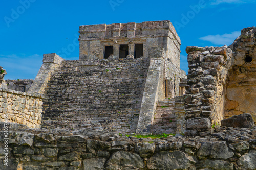 Ruins of ancient Tulum. Architecture of ancient maya. View with temple and other old buildings, houses. Blue sky and lush greenery of nature. travel photo. Wallpaper or background. Yucatan. Mexico.