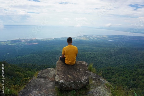 Man sitting on top of a mountain and enjoys the amazing view 