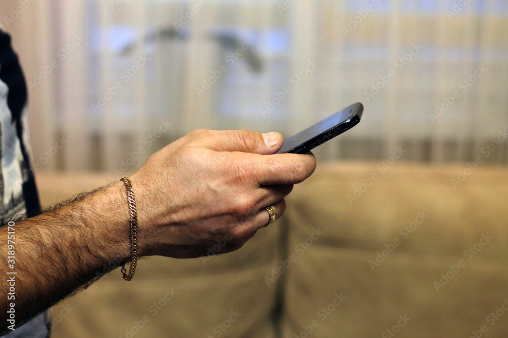 A man holds a smartphone in  his hand and looksat the screen