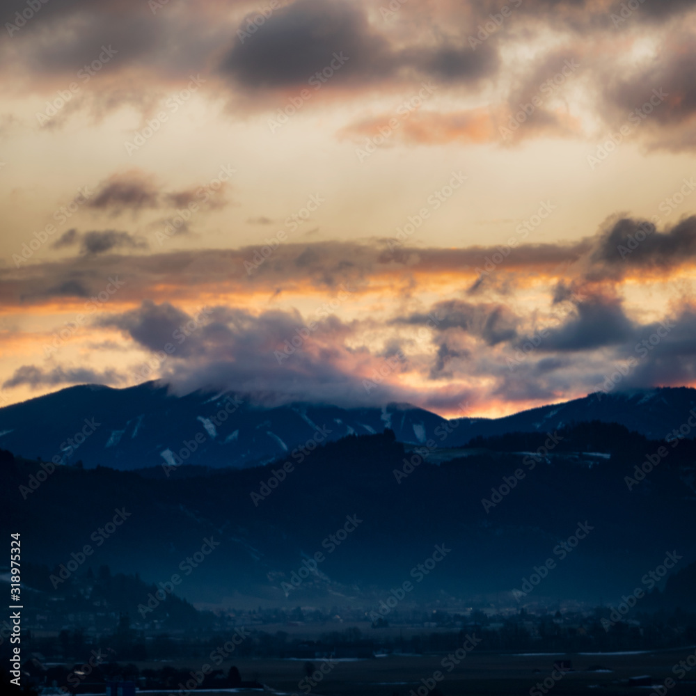 Silhouette of the Austrian Alps covered with clouds during sunset